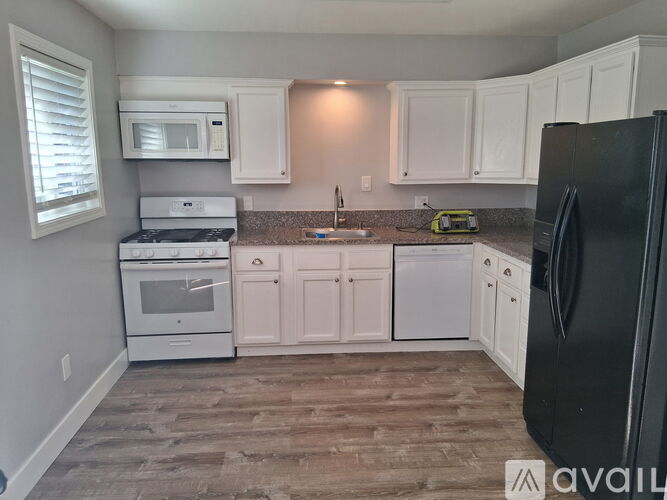 A kitchen with white cabinets and a black refrigerator.