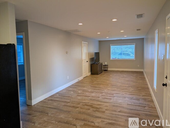 A spacious room with wooden flooring and a large window.