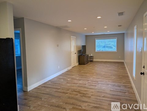 A spacious room with wooden flooring and a large window.