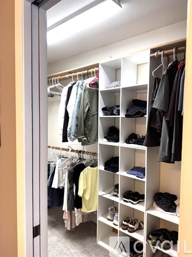 A walk in closet with clothes and shoes on shelves and hangers.