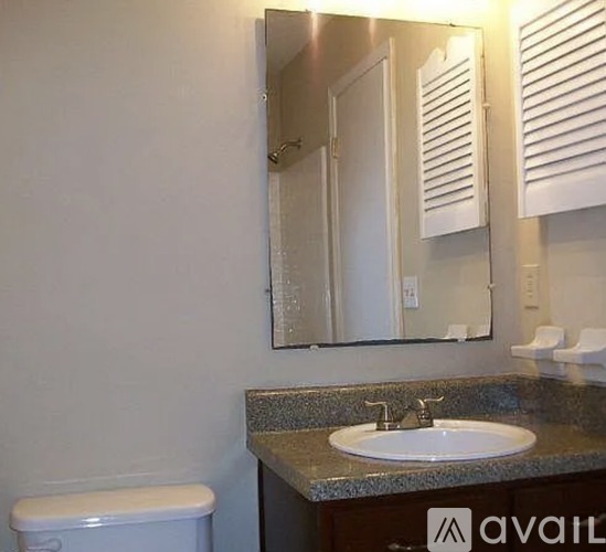 A bathroom with a toilet, sink, and mirror.