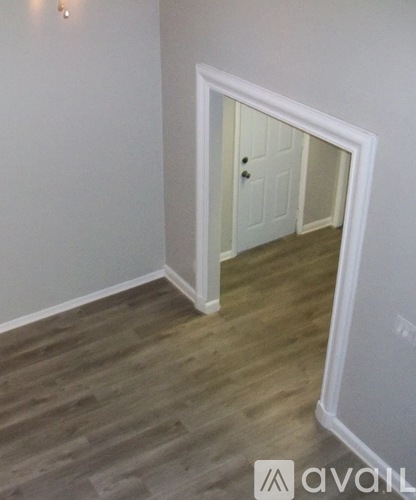 A hallway with a white door and wooden flooring.