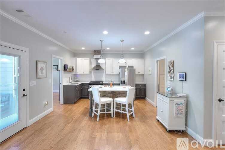 A well-lit kitchen with a dining table and chairs in the center.