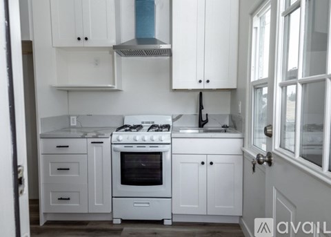 A white kitchen with a stove and sink.
