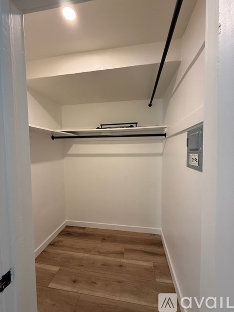 A white hallway with a wooden floor and a white door.