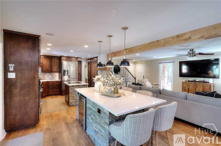 A modern kitchen with a wooden island and a dining area with a white table and striped chairs.