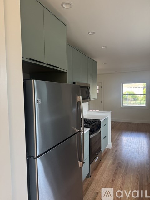 A kitchen with a stainless steel refrigerator and wooden floors.