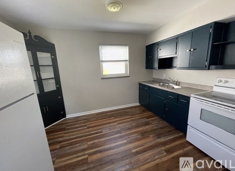 A kitchen with black cabinets and a white fridge.