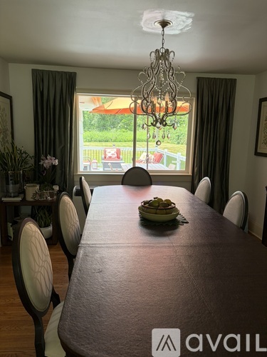 A dining room with a brown table and chairs with a chandelier hanging from the ceiling.