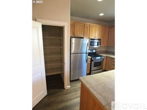 A kitchen with wooden cabinets and a stainless steel refrigerator.