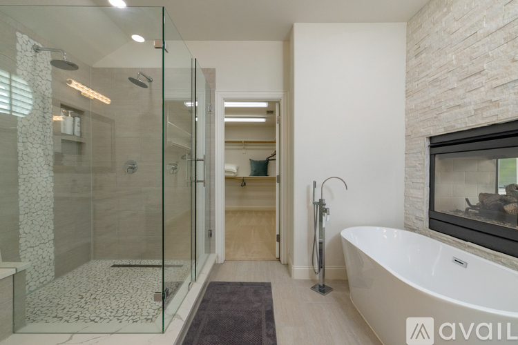A modern bathroom with a glass shower and a white bathtub.