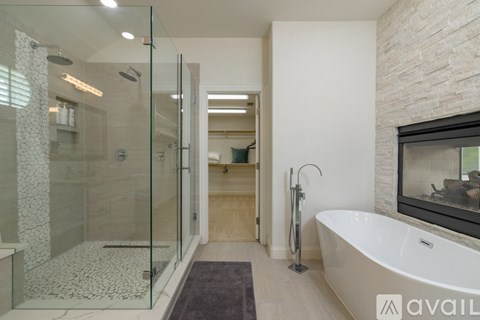 A modern bathroom with a glass shower and a white bathtub.