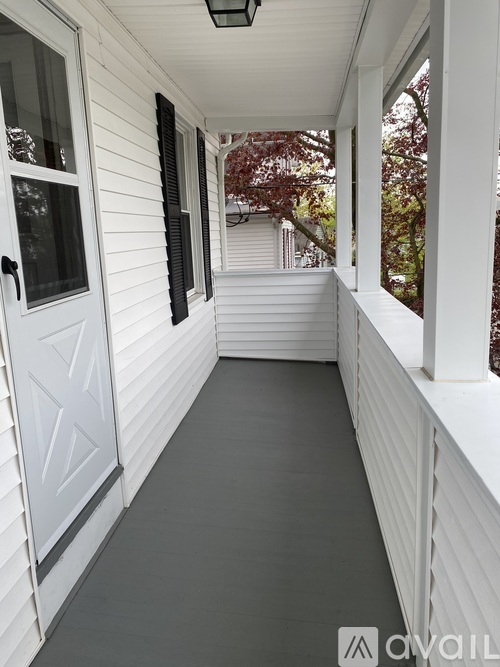 A white porch with a black door and a black lantern.