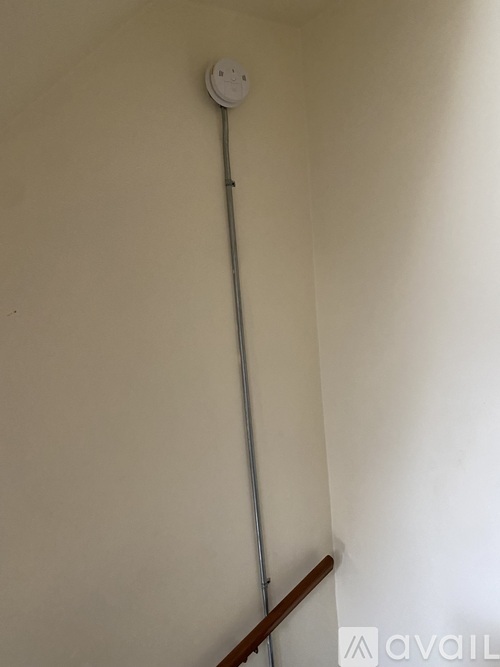 A white wall-mounted device with a long pole.