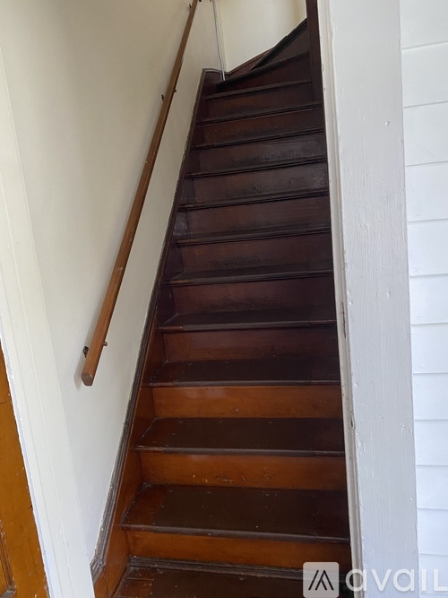 A brown wooden staircase with a white wall on the side.