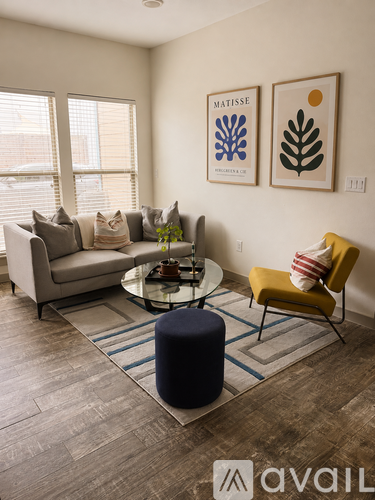 A living room with a sofa, a yellow chair, a coffee table, and two framed pictures on the wall.