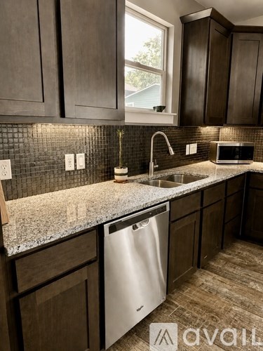 A kitchen with a stainless steel dishwasher and wooden cabinets.