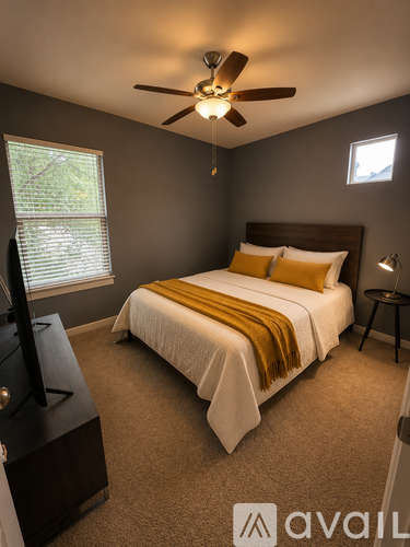 A bedroom with a bed, a ceiling fan, and a television.