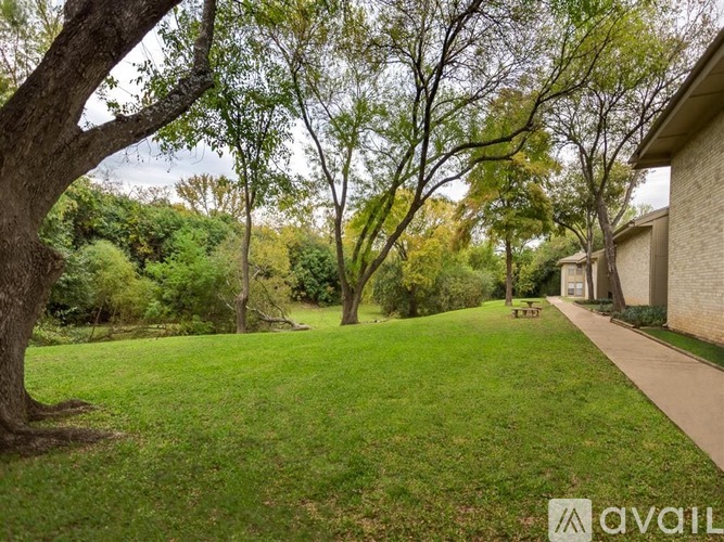 A tree in a yard with a house in the background.