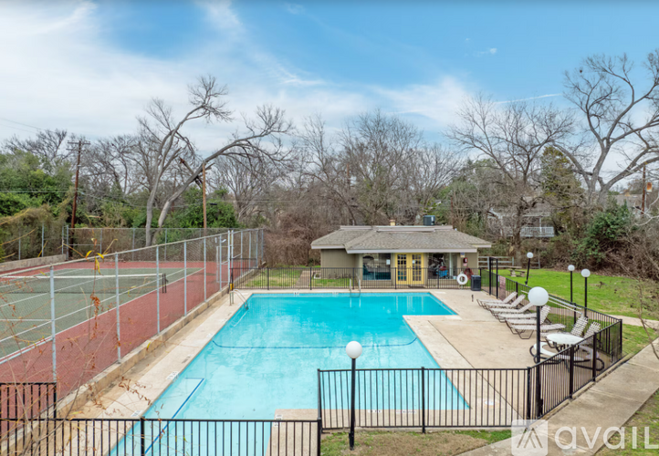 A pool with a black fence and a house in the background.