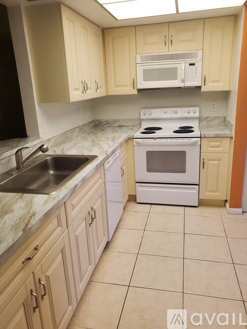 A kitchen with a white stove and sink.