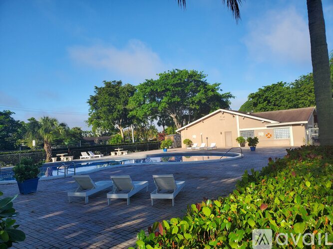 A pool area with lounge chairs and a building in the background.