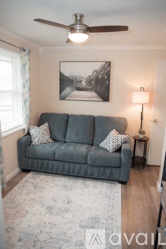 A living room with a grey couch and a ceiling fan.