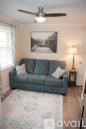 A living room with a grey couch and a ceiling fan.