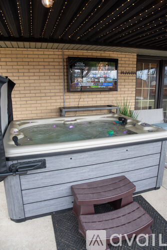 A hot tub with a television on the wall above it.
