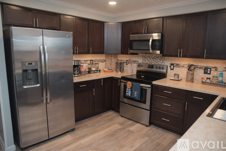 A kitchen with a stainless steel refrigerator and a microwave above the stove.