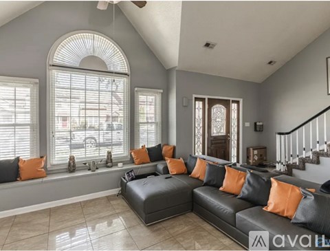A living room with a grey couch and orange pillows.