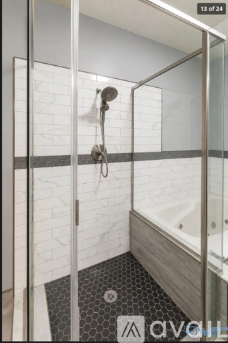 A bathroom with a white tile wall and a black and white hexagonal tile floor.