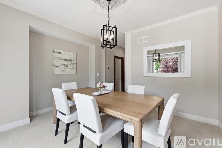 A dining room with a wooden table and white chairs.