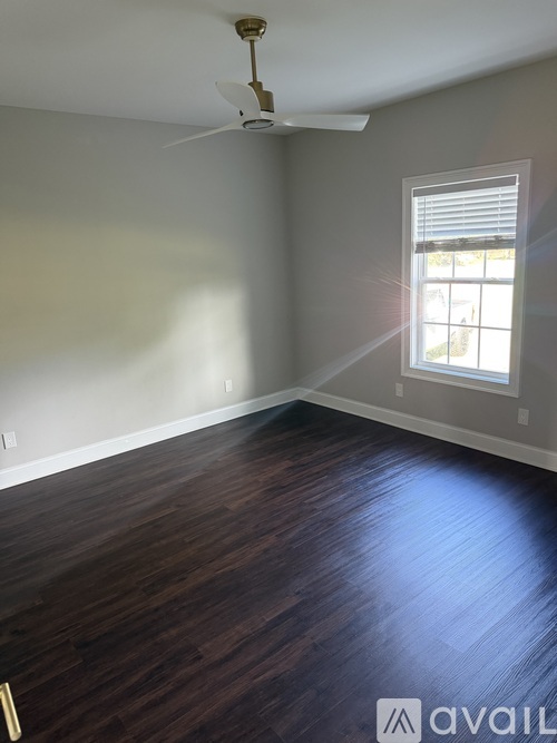 A room with a ceiling fan and a window with blinds.