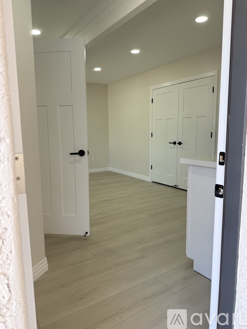 A hallway with white doors and a wooden floor.