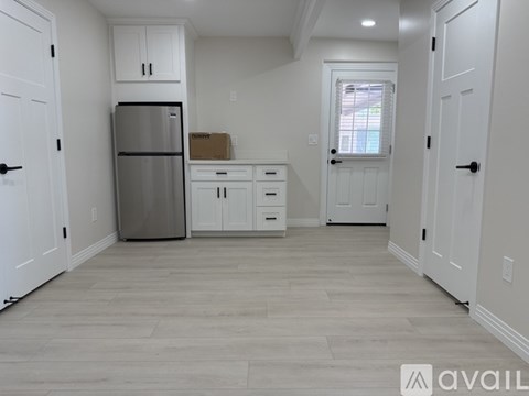 A kitchen with white cabinets and a refrigerator.