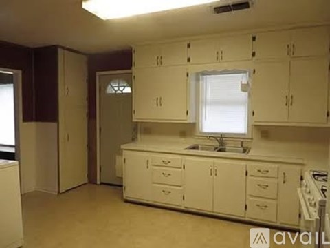 A kitchen with white cabinets and a window.