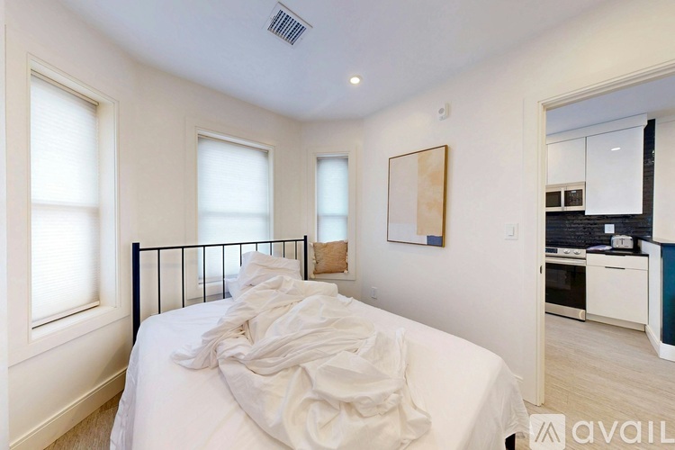 A bedroom with a white bed and a painting on the wall.