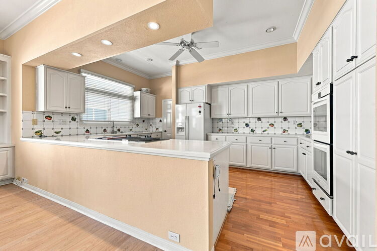 A kitchen with white cabinets and a wooden floor.