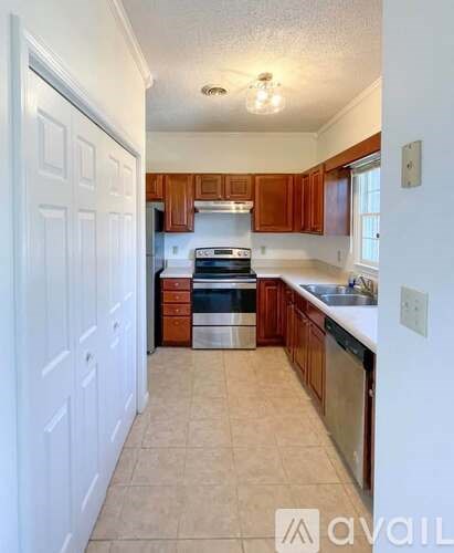 A kitchen with white walls and wooden cabinets.