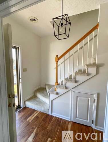 A wooden staircase with a white railing and a hanging light fixture.