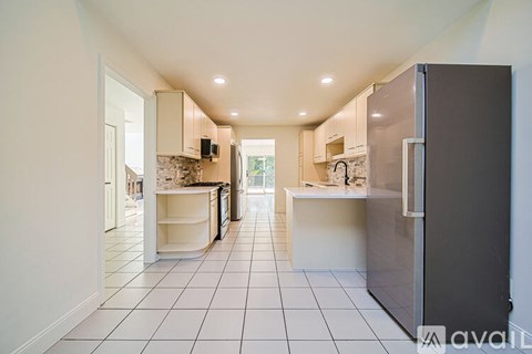 A kitchen with a refrigerator on the right and a counter with a sink in the middle.