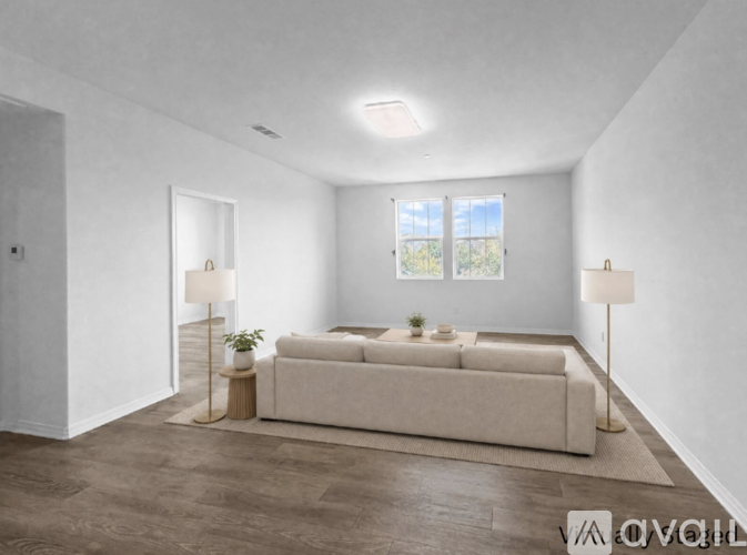 A living room with a white couch and two lamps.