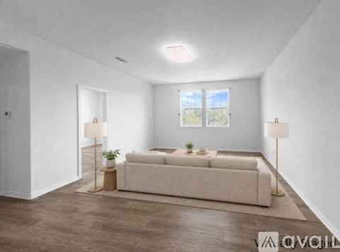 A living room with a white couch and two lamps.