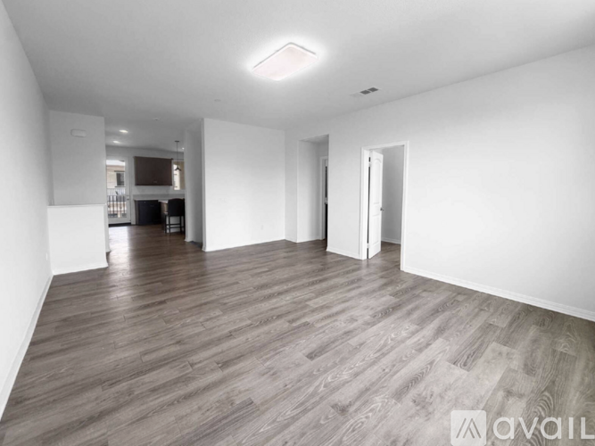 A spacious room with wooden flooring and white walls.