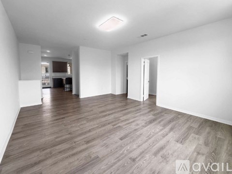 A spacious room with wooden flooring and white walls.