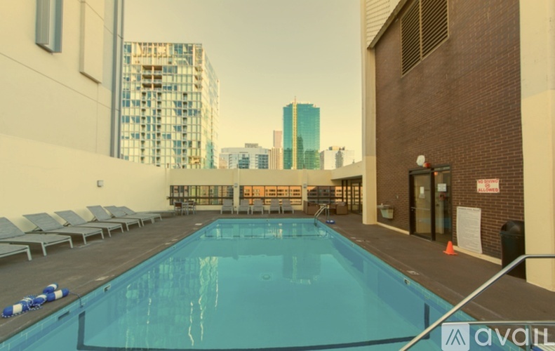 A large indoor swimming pool with lounge chairs and a city skyline in the background.