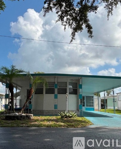A building with a blue and white facade and a palm tree in front.