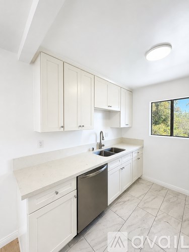 A kitchen with white cabinets and a black dishwasher.