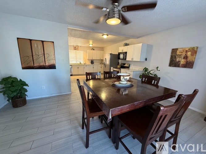 A dining room with a table set for two and a ceiling fan.